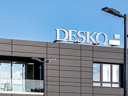 现代 DESKO 公司大楼，深色外墙，前景是旗帜和蓝天。