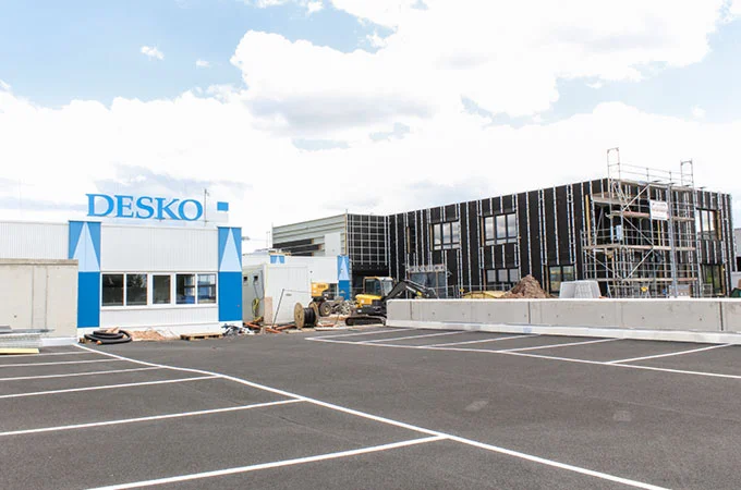 Edificio de la empresa DESKO con un nuevo edificio al fondo, obra con andamios y maquinaria de construcci&oacute;n en las instalaciones de la empresa.