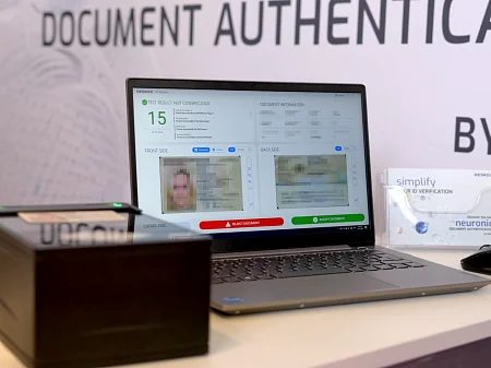 Estación de trabajo para la verificación de documentos con escáner y ordenador portátil, que muestra los resultados de una comprobación de identidad digital.