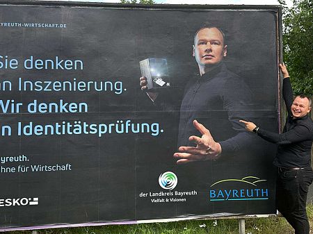 Wojciech Bujak, empleado de DESKO, delante de un cartel en el que aparece con un escáner DESKO en la mano.