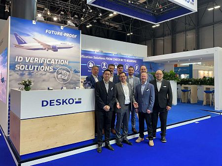 Cinco empleados de DESKO juntos frente al stand de la feria con soluciones de verificación de identidad y una gran presencia de marca.