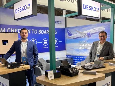 Dos empleados de DESKO están en el stand de la feria Global Airports Forum en Riad y miran a la cámara.