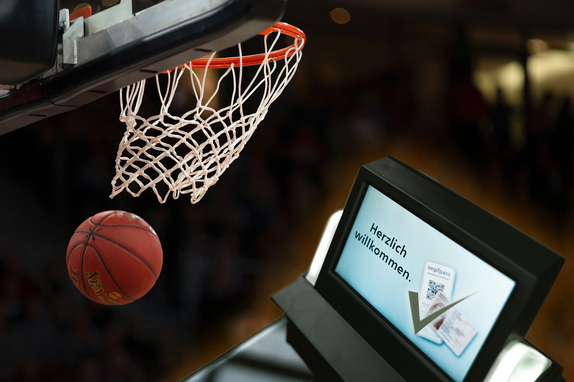 El bal&oacute;n de baloncesto pasa volando junto a la canasta, al lado una pantalla con un saludo y el c&oacute;digo QR para la prueba del certificado de vacunaci&oacute;n.