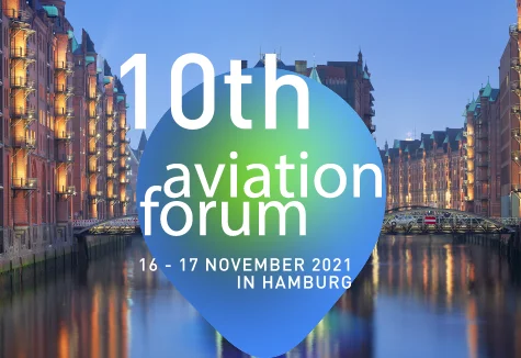 HafenCity Hamburgo al anochecer con los edificios iluminados en el paseo mar&iacute;timo, sobrepuestos con las letras del 10&ordm; Foro de la Aviaci&oacute;n.