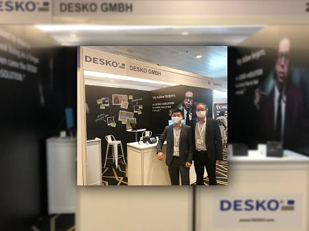 DESKO Messestand auf der Identity Week Asia 2022 in Singapur mit zwei Mitarbeitern vor der Produktpräsentation zur Dokumentenprüfung.