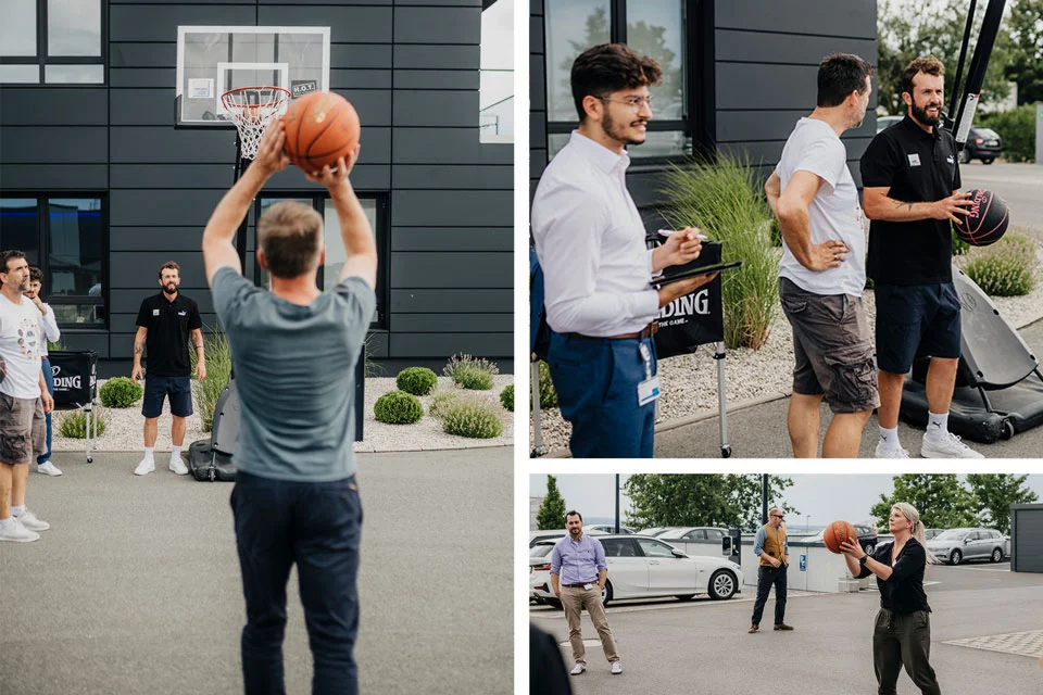 Varios empleados juegan al baloncesto en un patio de la empresa, lanzan a canasta y observan el partido frente al edificio de oficinas.