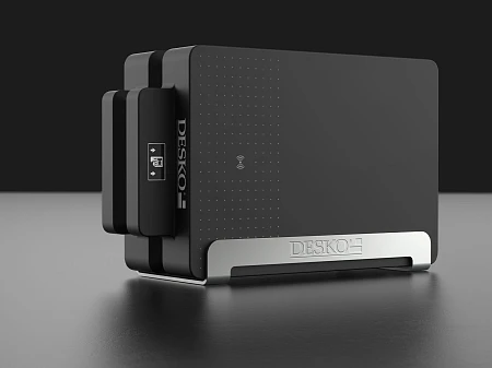 Dispositivo DESKO negro de diseño moderno sobre fondo oscuro, forma compacta con base metálica y símbolo NFC.
