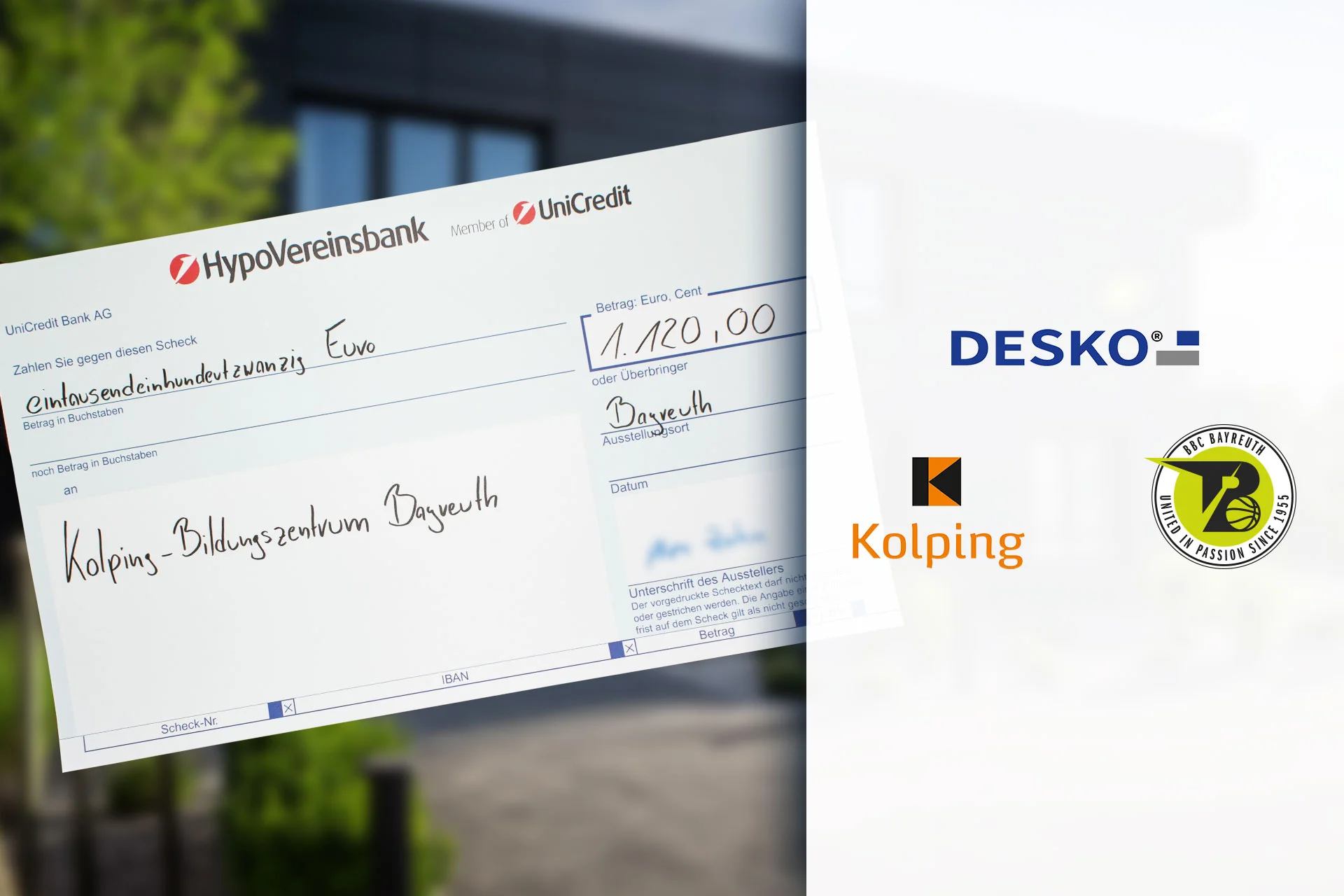 Cheque simb&oacute;lico del HypoVereinsbank por valor de 1.120 euros para el Centro de Formaci&oacute;n Kolping de Bayreuth, con los logotipos de DESKO y de los socios al lado.